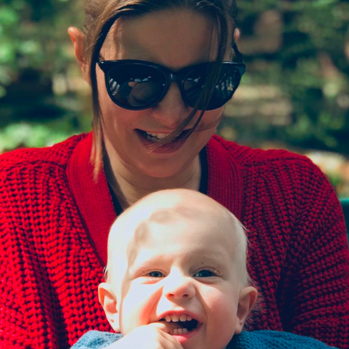 Woman in sunglasses smiling with a baby.