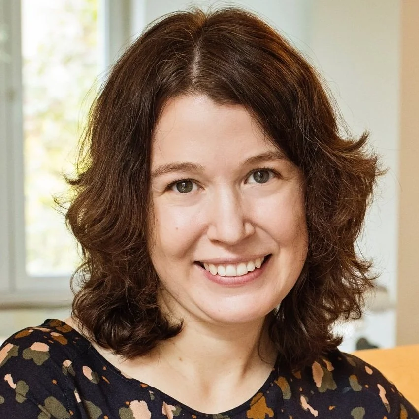 A smiling woman with wavy brown hair.